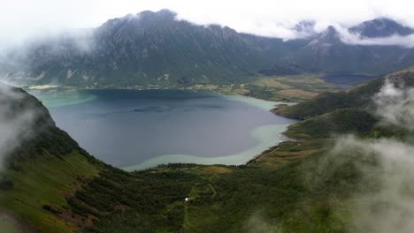 Drohne-Fliegt-Durch-Die-Wolken-Zu-Tropischem-Wasser-Mit-Umgebenden-Bergen-Auf-Den-Lofoten,-Norwegen