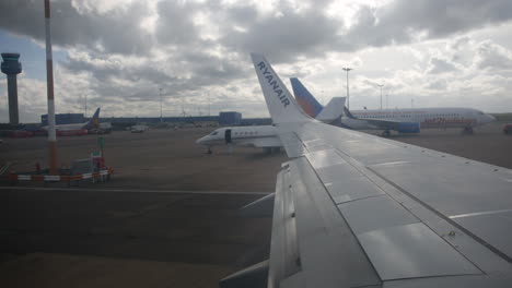 Ryanair-Flugzeug,-Das-Auf-Der-Landebahn-An-Einem-Flughafenfenster-Rollt,-Blick-über-Den-Flügel-Von-Der-Kabine-Aus