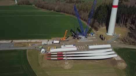 Construction-Site-Of-A-Wind-Turbine-With-Windmill-Parts-On-The-Ground---aerial-shot