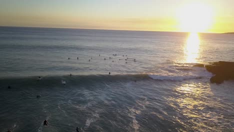 Sunset-Drone-shot-of-surfers-catching-waves-on-praia-do-estoril-on-Cascais