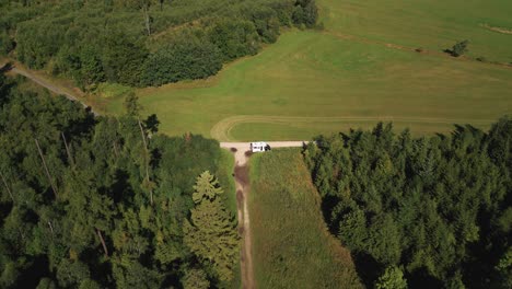 Aerial-shot-of-a-camper-camping-at-a-crossroads-between-forests-and-fields