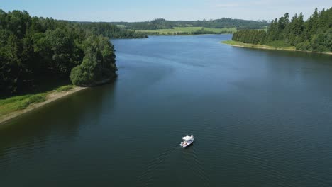 An-aerial-view-of-a-motorized-pleasure-boat-slowly-drifting-across-the-vast-lake-in-the-midst-of-forests-and-fields