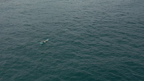Aerial-view-of-person-paddling-inflatable-kayak-on-ocean-water-below
