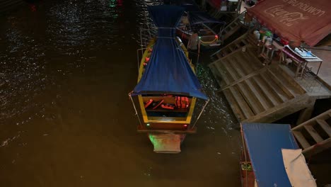Holzboote-Parken-An-Der-Seite-Der-Treppe,-Während-Ein-Einsamer-Bootsmann-Auf-Seine-Passagiere-Für-Die-Nachtkreuzfahrt-Im-Fluss-Mae-Klong-Auf-Dem-Schwimmenden-Markt-Amphawa-In-Samut-Songkhram,-Thailand,-Wartet