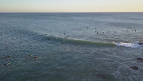 Aerial-video-of-surfers-in-motion-during-sunset-in-the-Atlantic-Ocean-in-Costa-da-Caparica,-Lisbon,-Portugal