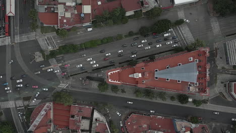 Cars-drive-on-large-one-way-city-street-below-urban-tracking-aerial
