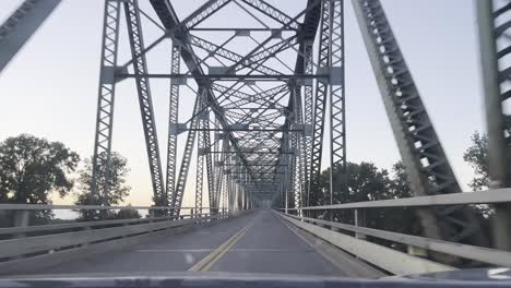 Pasando-Por-Debajo-De-Un-Enorme-Puente-Metálico-Durante-Un-Viaje-Por-Carretera,-Conduciendo-Placa
