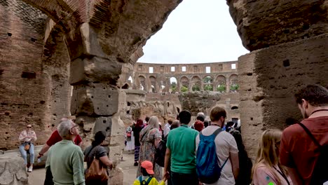A-group-of-sightseeing-tourists-walking-into-the-amphitheater-of-the-Coliseum,-Rome,-Italy