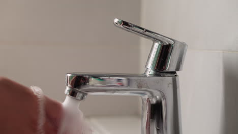 Young-female-opens-faucet-and-washes-hands-thoroughly