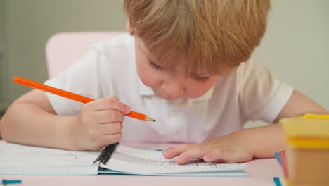 Preschooler-draws-picture-with-pencil-sitting-at-desk