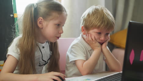 Smiling-girl-turns-on-cartoons-on-laptop-to-bored-brother