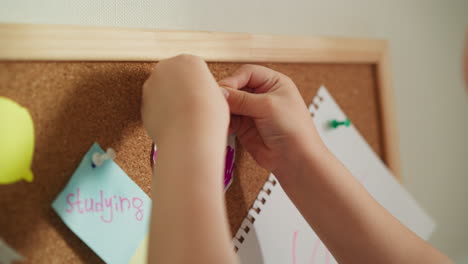 Child-hands-pins-bright-colourful-picture-to-cork-board