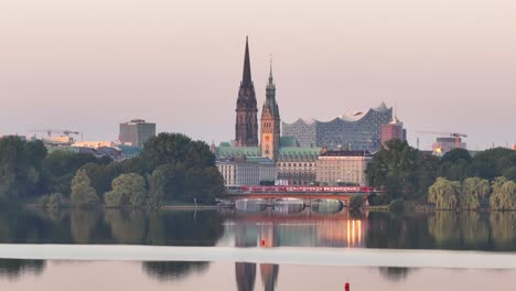 Skyline-of-Hamburg,-Germany,-Townhall-and-Elbe-philharmonic-hall-,-cars-and-a-train-crossing-the-Kennedy-Bridge