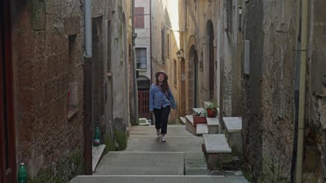 Mujer-Solitaria-Subiendo-Las-Escaleras-En-El-Antiguo-Pueblo-De-Pitigliano,-Toscana-Italia