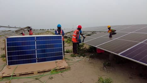 Ingenieros-Y-Técnicos-Que-Trabajan-Instalando-Conjuntos-De-Paneles-Solares-Fotovoltaicos-Bifaciales-En-Una-Granja-De-Proyectos-Solares-En-Gambia,-África-Subsahariana-Occidental