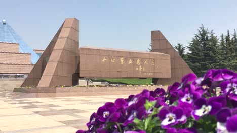 Monument-in-Longhua-Gardens-Park-near-Martyrs-Memorial-in-Shanghai,-China-behind-blurred-viola-flowers-with-a-bee