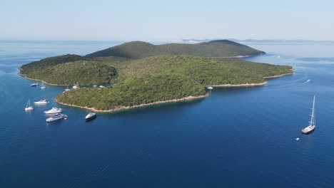 Boats-sail-near-idyllic-Green-Island-in-Ionian-Sea-at-Syvota,-Epirus,-Greece