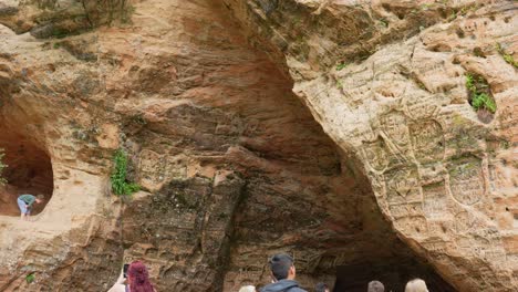 Turistas-Explorando-La-Cueva-De-Gutmans-De-Arenisca-Con-Antiguas-Inscripciones-En-Las-Paredes,-Letonia