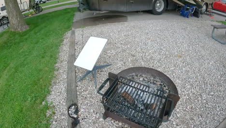 Satellite-antenna-near-a-camp-fire-ring-and-RV-coach-in-a-campground