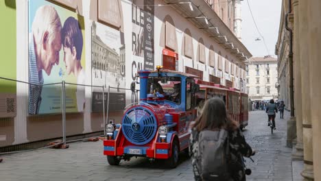 Smal-tourist-sightseeing-train-in-Via-dell-Archiginnasio-street-and-Portico-del-Pavaglione-in-Bologna,-Italy-near-Bologna-Cathedral