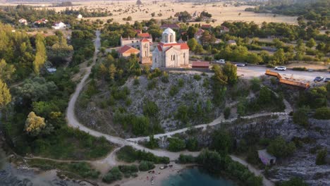 Serbian-Orthodox-Church-of-the-Ascension-of-the-Lord,-Drone-shot-revealing-popular-Cetina-River-spring-Izvor-Cetine-in-Omis,-Croatia