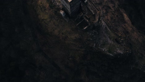 Top-view-drone-shot,-middle-ages-hilltop-tower-fortification-ruins-at-dusk