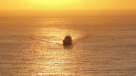 Aerial-View-Of-Silhouette-Of-Ship-Sailing-Off-Zoutelande-With-Golden-Orange-Sunset-Sky