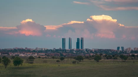 Timelapse-cloudy-and-stormy-sky-in-Madrid-skyline-during-sunset-golden-hour-with-flock-of-sheep-trees-and-rural-land-as-foreground