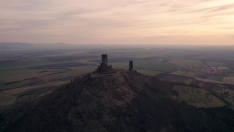 Medieval-hilltop-castle-towers-at-dusk,-cinematic-establishing-drone-shot