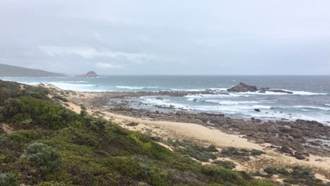Empty-sand-and-rocky-beach-in-Western-Australia-with-Gull-Rock-near-Cape-Naturaliste-in-stormy-weather