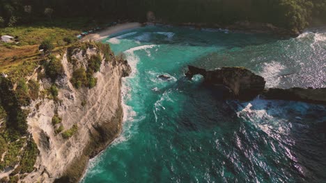 Eine-Klippe-Am-Strand-Von-Atuh-Mit-Panoramablick-Auf-Die-Insel-Batupadasan,-Den-Sonnigen-Himmel-Und-Das-Kristallklare-Blaue-Wasser-Darunter
