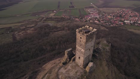 Orbiting-view-drone,-hilltop-medieval-castle-tower-ruins-with-village-below