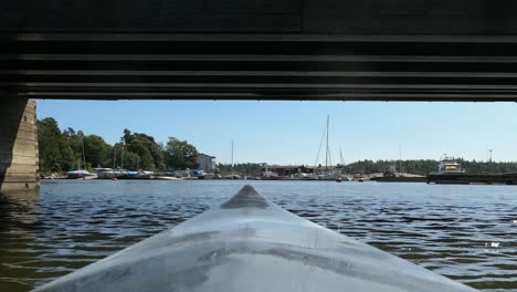 Kayaking-under-bridge,-kayak-bow-view,-approaching-harbor,-point-of-view
