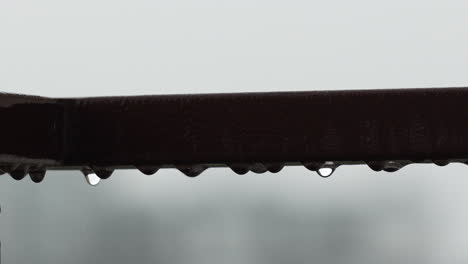 Macro-Shot-Of-Rain-Drops-Hanging-From-Abstract-Metal-Pole-With-Bokeh-Background