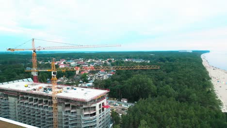 Stunning-drone-footage-of-a-new-luxury-hotel-complex-being-built-on-a-picturesque-Baltic-Sea-beach-where-walkers-stroll-during-sunset