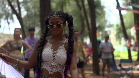 African-woman-with-ponytail-style-hair-extensions-dancing-in-outdoor-space-and-waving-Chinese-paper-fan,-filmed-as-medium-close-up-shot-in-slow-motion
