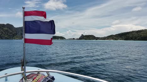Thai-Ferry-Arrival-from-Krabi-to-Koh-Phi-Phi,-Flag-Fluttering-in-the-Wind,-Offering-Breathtaking-Ocean-Panorama-and-Picturesque-Island-Landscape