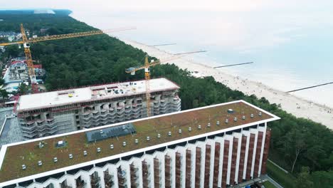 Stunning-drone-footage-of-a-new-luxury-hotel-complex-being-built-on-a-picturesque-Baltic-Sea-beach-where-walkers-stroll-during-sunset