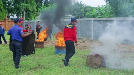 Los-Bomberos-Del-Servicio-De-Bomberos-Del-Distrito-De-Cirebon-En-Indonesia-Están-Realizando-Una-Simulación-De-Extinción-De-Un-Incendio-Con-Un-Paño-Húmedo-En-Un-Espacio-Abierto.