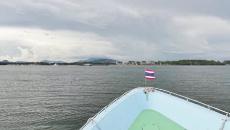 Llegada-Del-Ferry-Tailandés-Desde-Las-Islas-Koh-Phi-Phi-Con-La-Bandera-Ondeando-Al-Viento,-Mostrando-Una-Vista-Panorámica-Del-Océano-Y-El-Impresionante-Paisaje-De-Tailandia