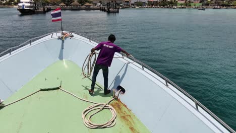 Thai-Ferry-Nears-Koh-Phi-Phi-Pier,-Deckhand-Prepares-to-Secure-Rope,-Set-Against-Serene-Island-Backdrop