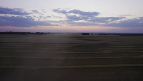 Fast-low-drone-flight-over-combine-harvester-harvesting-grains-at-twilight