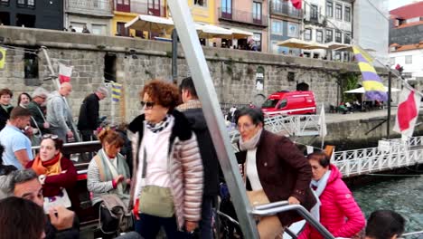 Group-of-old-women-boarding-Rabelo-boat-crowded-with-tourists-in-Cais-da-Ribeira,-Porto