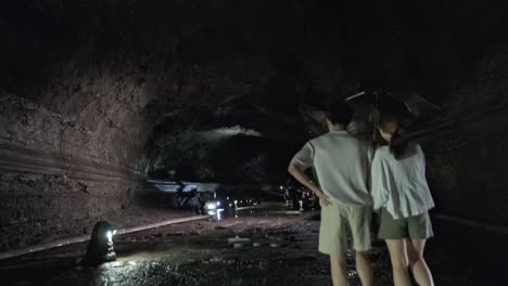 Pan-down-and-tracking-shot-of-couple-walking-through-the-tunnel-water-dripping