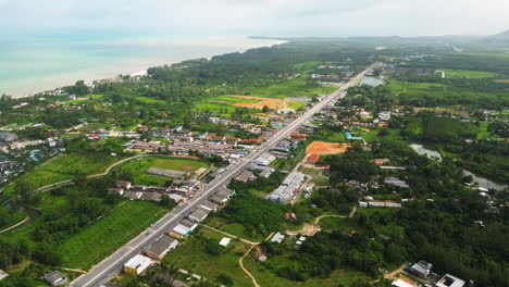 Coastal-town-with-highway-road-in-Thailand,-aerial-drone-view