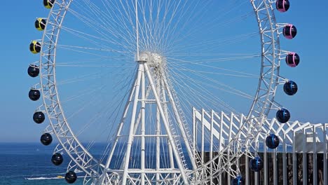 Sokcho-Eye---Ferris-Wheel-Tilt-Down-Aerial-Close-up,-Sokcho-City-on-Summer-Sunny-Day
