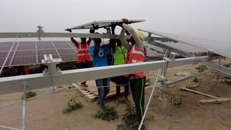 Professional-engineers-working-as-team-in-Africa-installing-bifacial-solar-panels-inside-photovoltaic-farm-in-wilderness