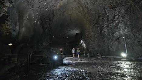 Static-wide-shot-of-cave-tunnel-with-people-walking-through