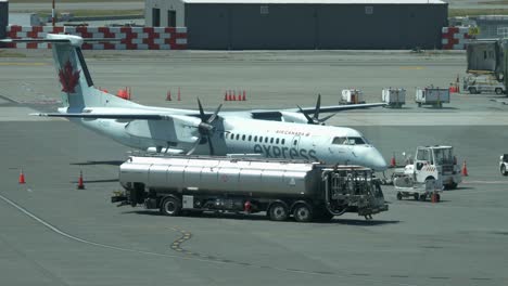Fuel-Truck-with-Jet-A1-Kerosene-Driving-at-Airport-Apron-with-Plane