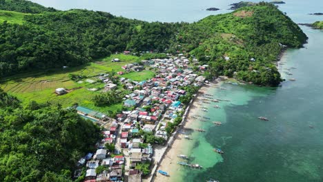 Casas-Sencillas-En-La-Costa-De-Filipinas-Con-Muchos-Barcos-Pesqueros-Primitivos,-Vista-De-Drones